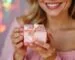 Femme souriante tenant un cadeau bijou dans une petite boîte rose à ruban