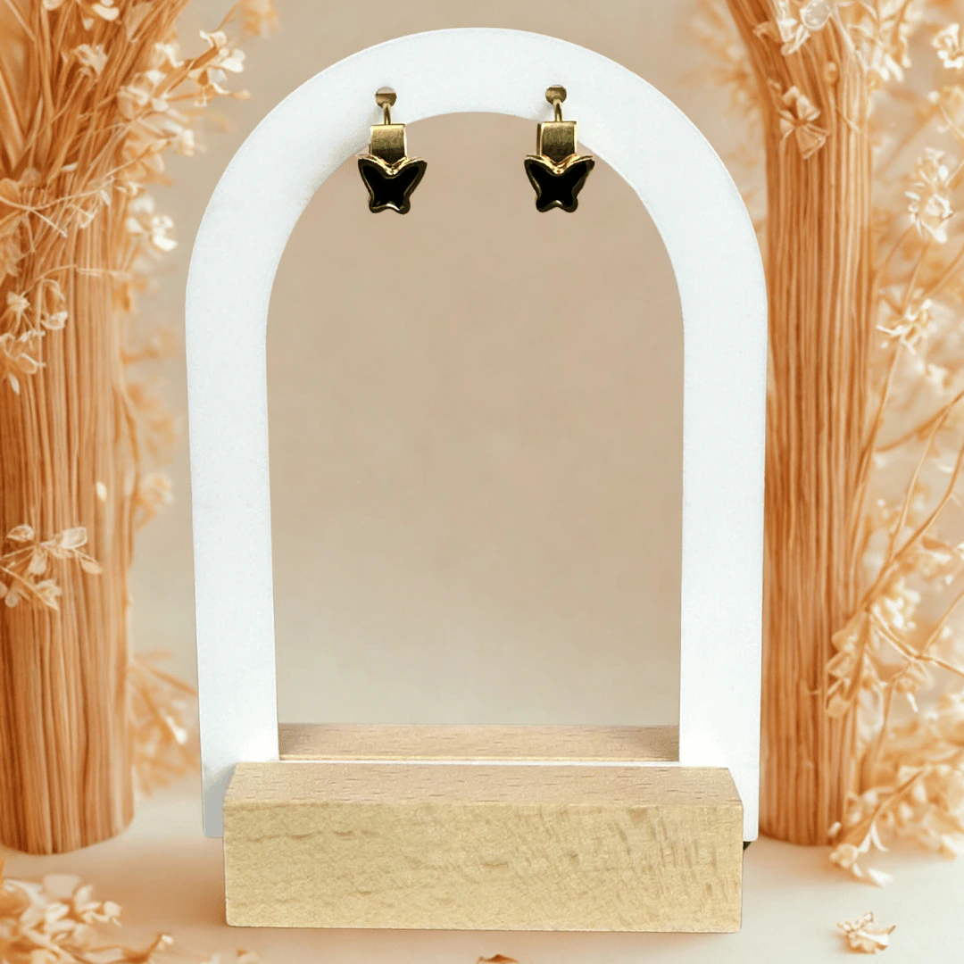 Petites créoles dorées à papillon noir suspendues à un présentoir arche blanc
