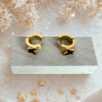 Boucles d'oreilles anneaux papillon noir dorées sur un socle en bois, décor d'étoiles dorées