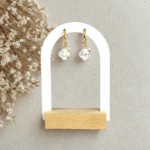 Boucles d'oreilles trèfle en cristal blanc irisé sur petites créoles dorées, présentoir arche