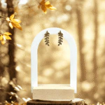Clous d'oreilles branche de feuilles dorées accrochés à un présentoir arche blanc, ambiance automnale