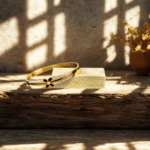 Jonc doré trèfle noir à rails de strass appuyé sur un bloc de bois dans la lumière du soleil