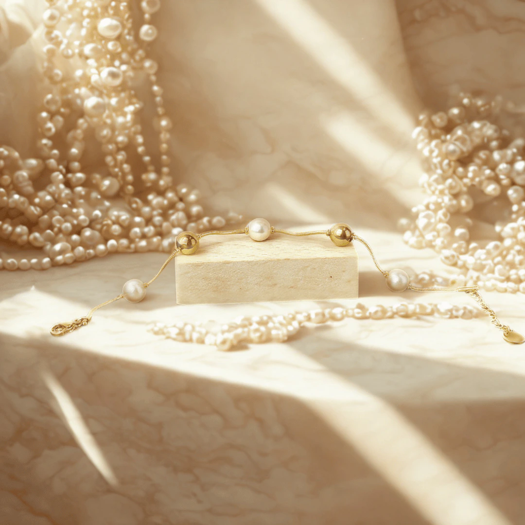 Bracelet fin perles blanches et billes dorées posé sur un bloc, entouré de rangs de perles
