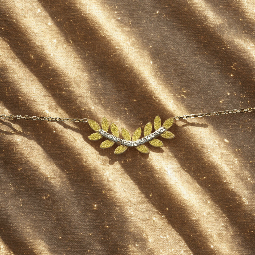 Bracelet laurier scintillant à feuilles dorées et rang de cristaux posé sur un tissu doré pailleté
