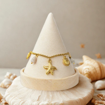 Bracelet étoile de mer et coquillages doré présenté sur un cône, décor de coquillages