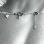 Gros plan noir et blanc du bracelet argenté à cœur pavé de cristaux et perle noire posé sur la peau