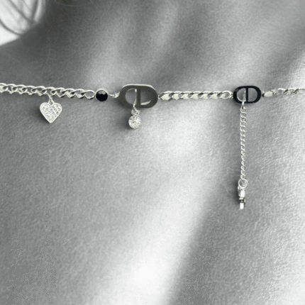 Gros plan noir et blanc du bracelet argenté à cœur pavé de cristaux et perle noire posé sur la peau