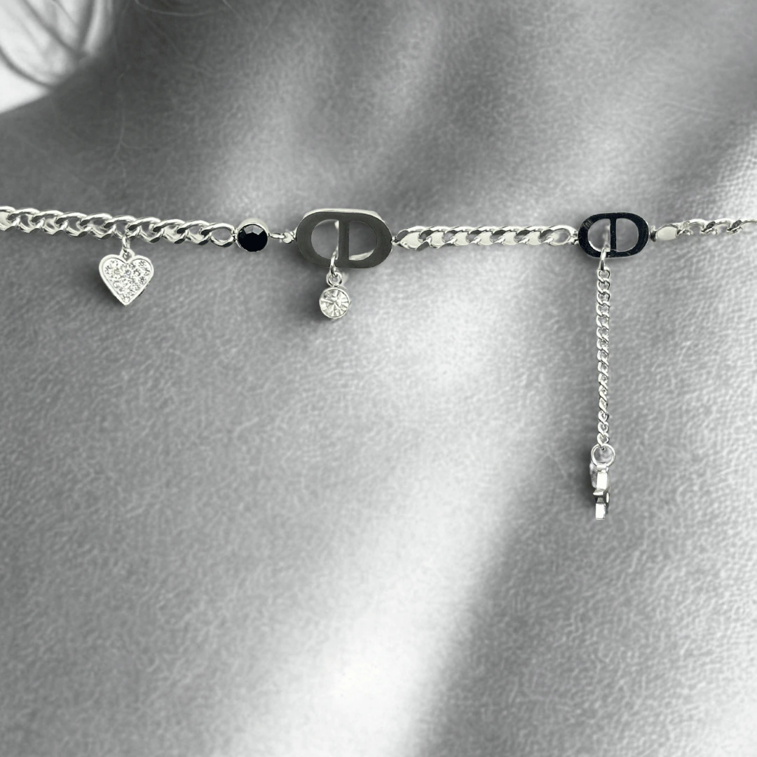 Gros plan noir et blanc du bracelet argenté à cœur pavé de cristaux et perle noire posé sur la peau