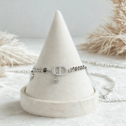 Bracelet chaîne fine argenté femme à maillon ovale, cœur pavé de cristaux et perle noire sur présentoir cône