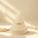 Bracelet chaîne fine doré femme à barrette pavée de strass et trio de cristaux mobiles sur présentoir cône