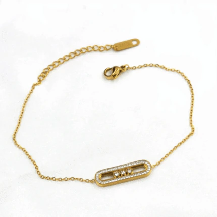 Bracelet chaîne fine dorée à barrette ovale scintillante posé à plat avec fermoir et chaînette de réglage