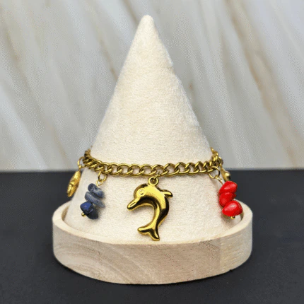 Bracelet charms marins doré présenté sur un cône, breloque dauphin et pierres colorées