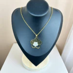 Collier pendentif fleur dorée ajourée à cœur pavé de strass sur buste présentoir noir