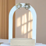 Puces d'oreilles fleur dorées ajourées à centre en strass sur présentoir arche blanc