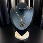Collier trèfle doré, pendentif ajouré aux feuilles en forme de cœur, sur buste présentoir noir
