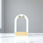 Puces d'oreilles dorées à cristal rond brillant présentées sur un présentoir arche blanc