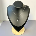 Collier pendentif volutes à finition foncée et cristal sur chaîne fine argentée, buste présentoir noir