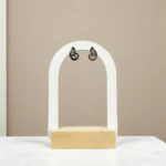 Puces d'oreilles volutes à finition foncée et petit cristal sur présentoir arche blanc