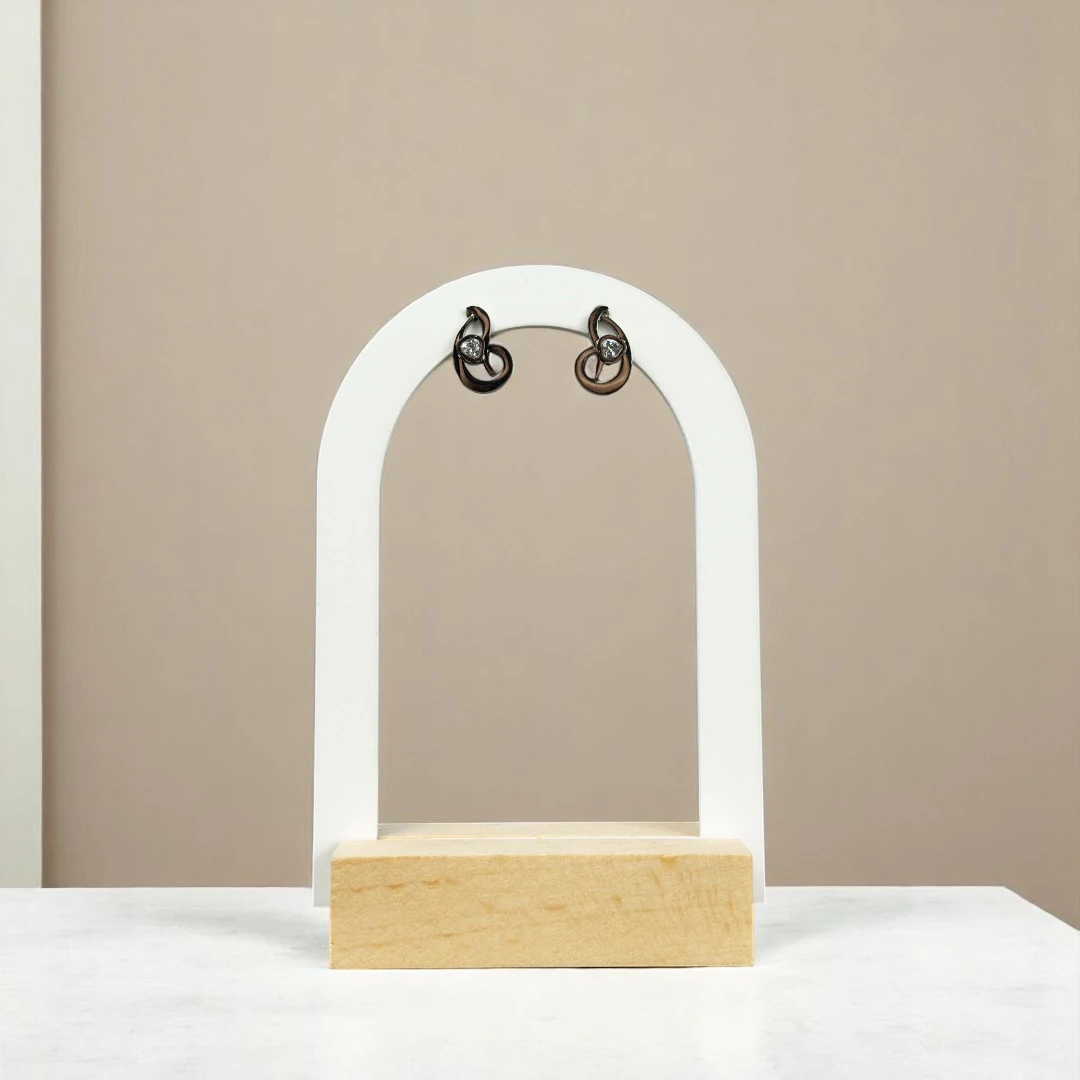 Puces d'oreilles volutes à finition foncée et petit cristal sur présentoir arche blanc