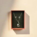 Parure élégance abstraite dans son coffret : collier pendentif volute et puces d'oreilles assorties