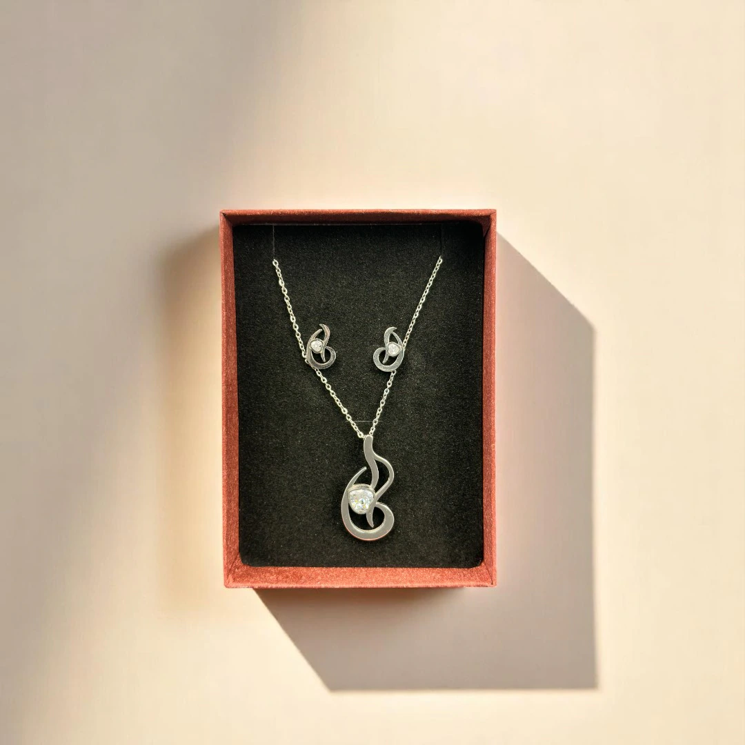 Parure élégance abstraite dans son coffret : collier pendentif volute et puces d'oreilles assorties
