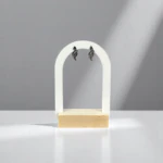 Boucles d'oreilles courbes scintillantes à finition foncée et strass sur présentoir arche blanc