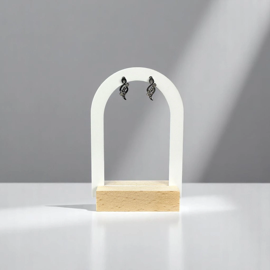 Boucles d'oreilles courbes scintillantes à finition foncée et strass sur présentoir arche blanc