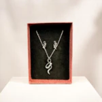 Parure courbes scintillantes dans son coffret rose : collier pendentif sinueux et boucles d'oreilles