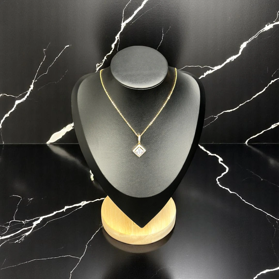 Collier doré à pendentif solitaire cristal carré serti en losange sur buste noir, fond marbre noir