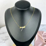 Collier libellule dorée à corps scintillant présenté sur un buste noir, chaîne fine dorée
