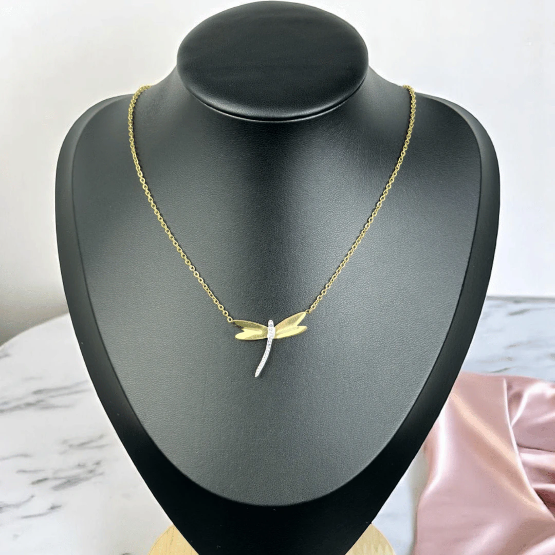 Collier libellule dorée à corps scintillant présenté sur un buste noir, chaîne fine dorée