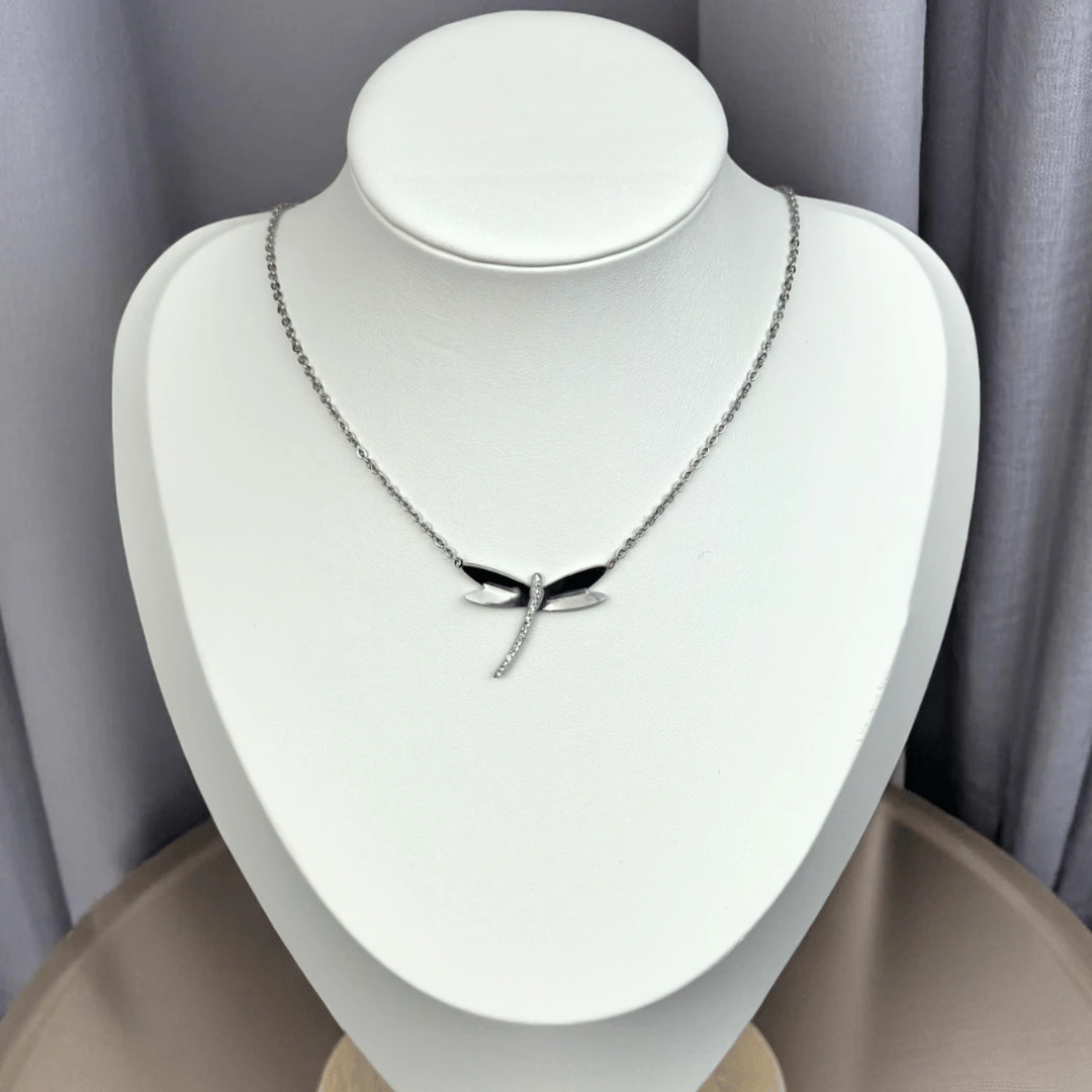 Collier libellule argentée à corps scintillant présenté sur un buste blanc