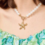 Femme portant un collier de perles blanches à pendentif étoile de mer dorée, vue en gros plan