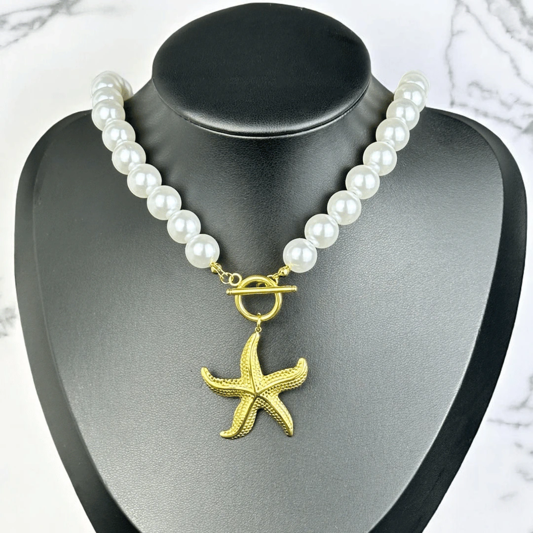 Collier de grosses perles blanches à pendentif étoile de mer doré présenté sur un buste noir