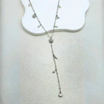 Collier long en Y argenté à étoile de mer et pendentif coquillage posé à plat sur fond blanc texturé