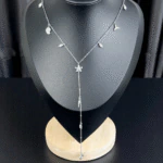 Collier Y sirène argenté à charms marins et petites perles présenté sur un buste noir