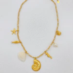 Collier chaîne dorée à charms marins posé à plat : ammonite, coquillage blanc, poisson et étoile de mer