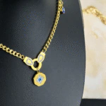 Vue de côté du collier œil protecteur doré : médaillon octogonal, attache strass et charm bleu