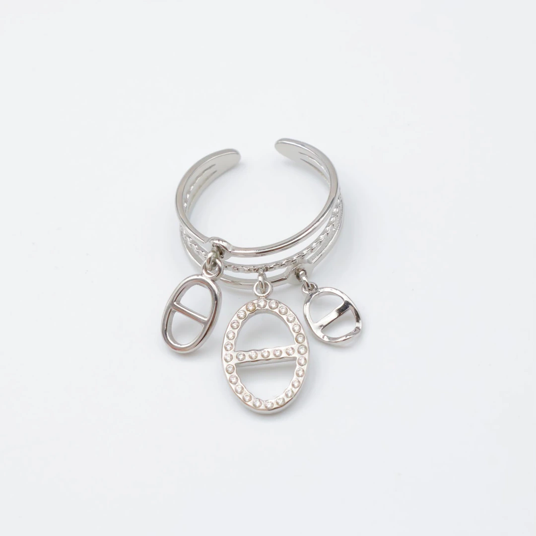 Bague ouverte argentée à anneaux multiples et trois charms ovales ajourés, fond blanc