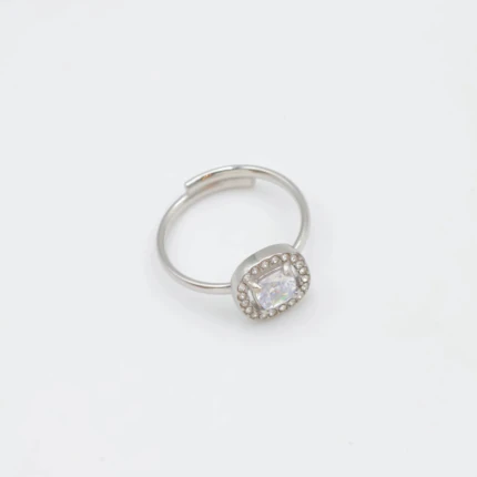Bague femme argentée ajustable à pierre carrée brillante entourée de petits strass, sur fond blanc