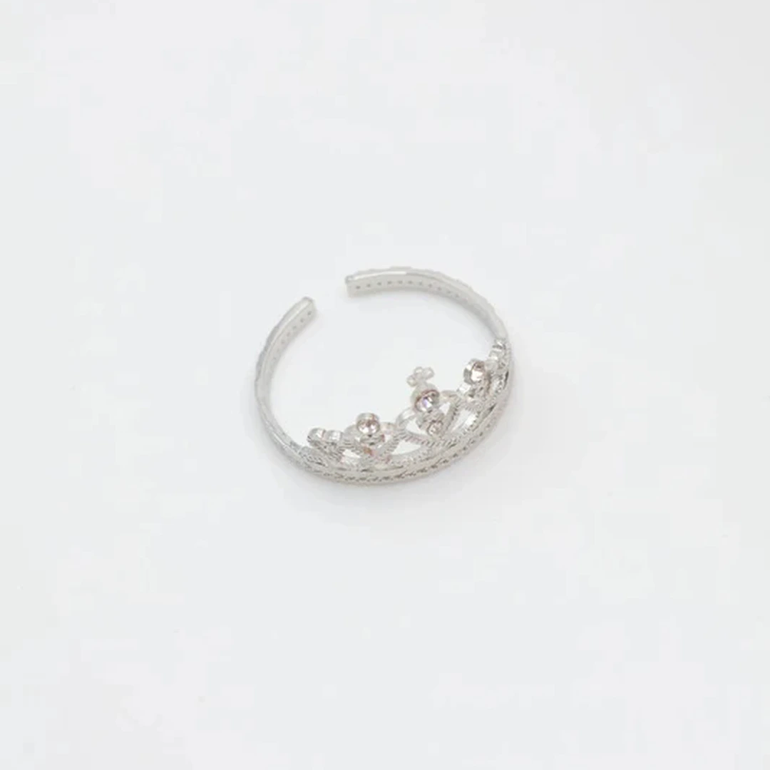 Bague couronne argentée ouverte à fines volutes et petits strass brillants, vue sur fond blanc
