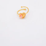 Bague ouverte dorée à cœur rose pailleté et fleur rose en relief, extrémités boules, fond blanc