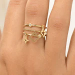 Bague femme dorée multi-rangs à charms trèfle, étoile et losange ajouré portée au doigt