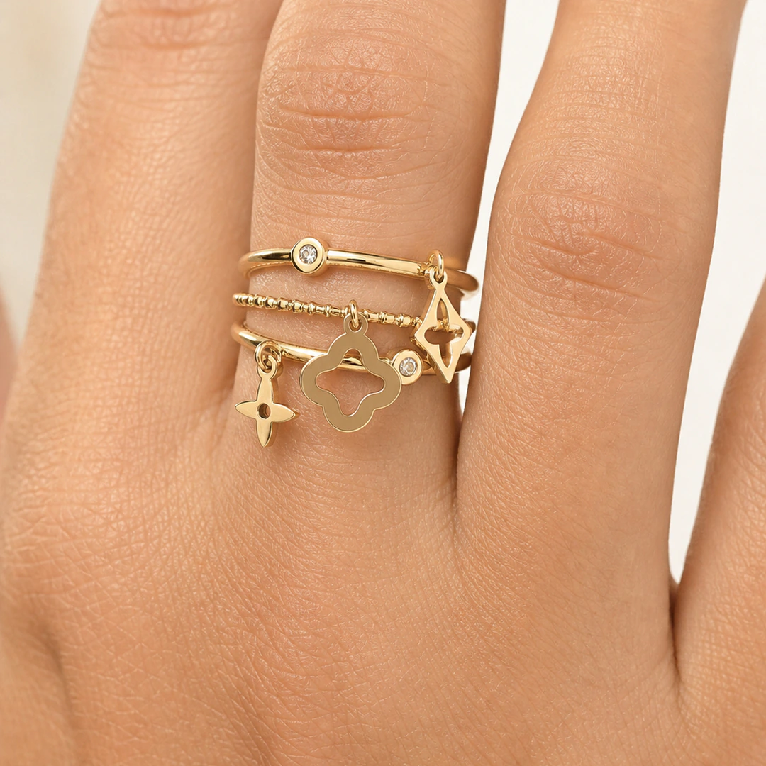 Bague femme dorée multi-rangs à charms trèfle, étoile et losange ajouré portée au doigt