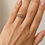 Bague femme dorée fine à trois petits trèfles sertis de pierres vertes, roses, bleues et violettes portée au doigt