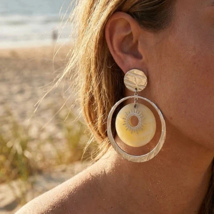Boucles d'oreilles pendantes femme anneau argenté et disque jaune motif soleil portées à l'oreille