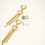 Paire de créoles dorées à cercle serti de strass, carré blanc et longues franges en chaîne sur fond blanc