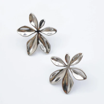 Paire de boucles d'oreilles fleur argentées aux pétales bombés et brillants sur fond gris clair