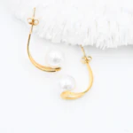 Boucles d'oreilles demi-créoles dorées ouvertes à perle blanche posées à plat, poussoirs visibles