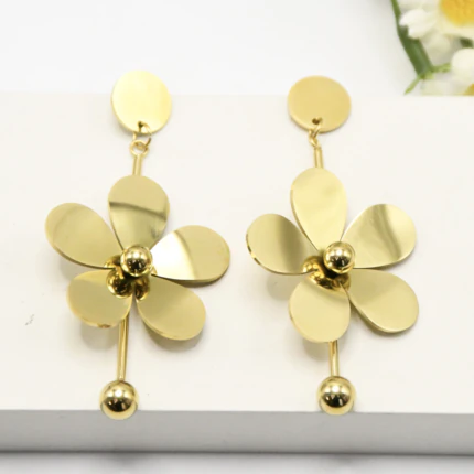 Paire de boucles d'oreilles longues dorées à fleur aux cinq pétales lisses et centre boule sur fond blanc